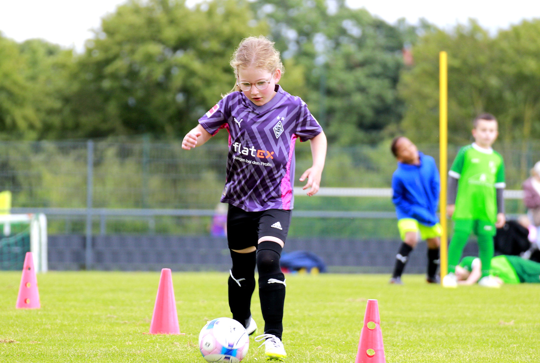 Kind setzt zum Dribbling zwischen Hütchen an