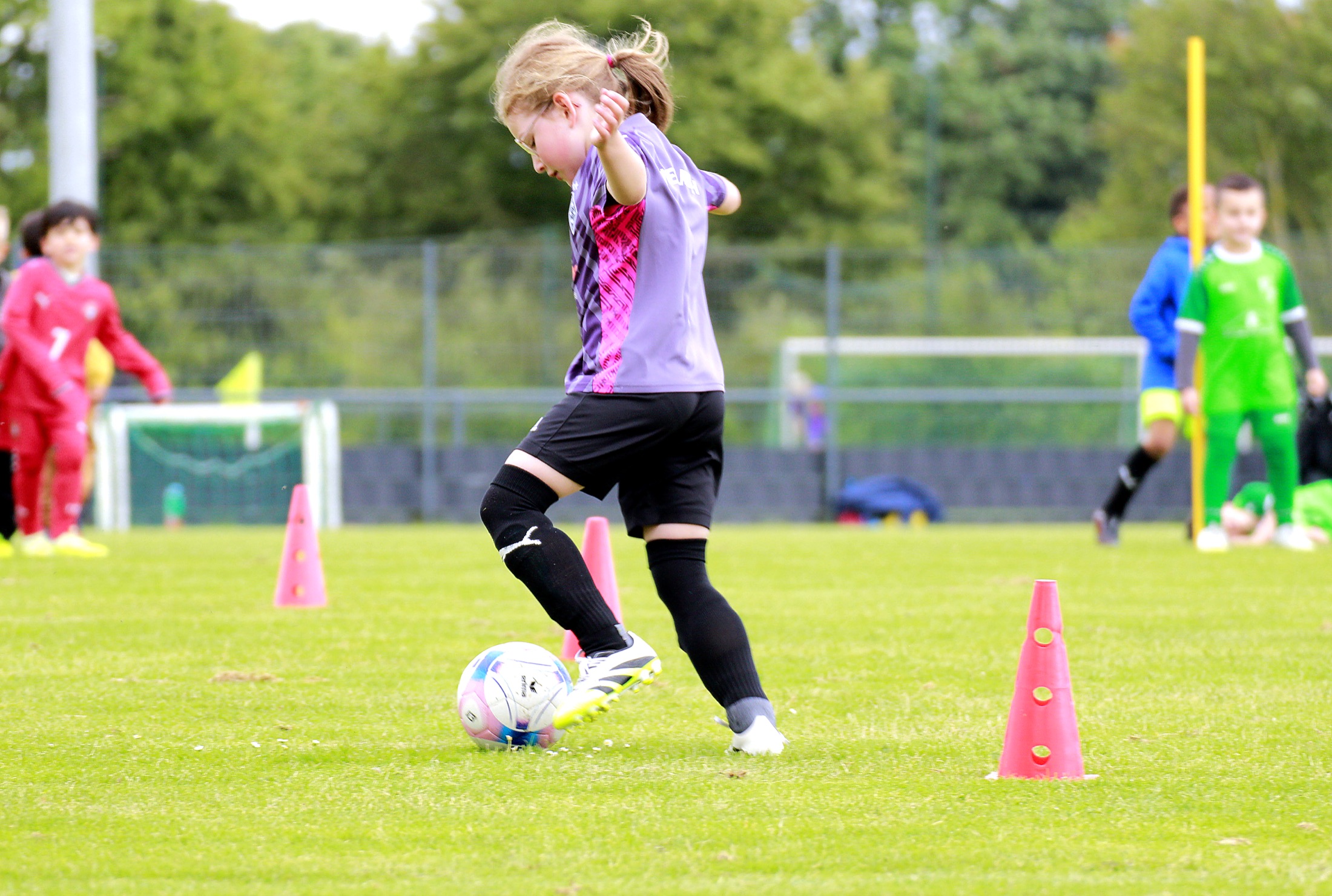 Kind im roten Trikot spielt den Ball