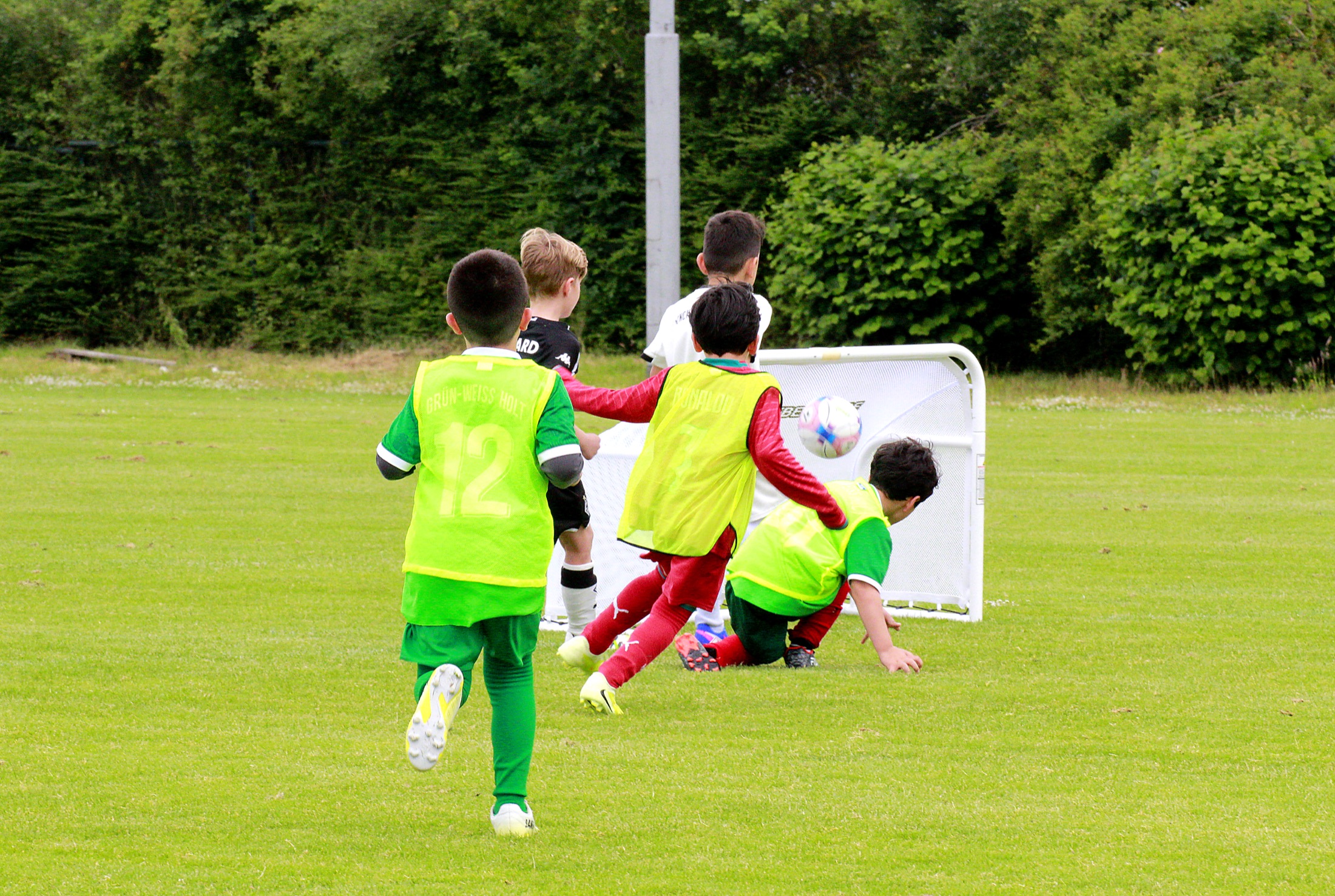 Kind im roten Trikot führt den Ball